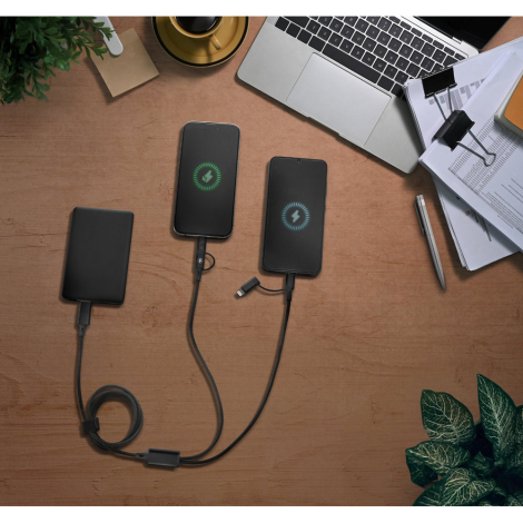 Câble branché simultanément à deux smartphones en charge sur un bureau, sans marquage visible.