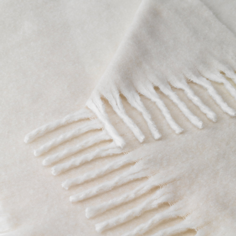 Gros plan sur la texture douce du plaid et les finitions à franges, sans marquage apparent.