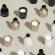 Ensemble de diffuseurs et bougies parfumées en plusieurs coloris mats — noir, doré et blanc — chacun portant un marquage visible