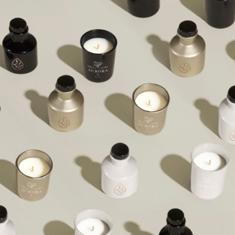 Ensemble de diffuseurs et bougies parfumées en plusieurs coloris mats — noir, doré et blanc — chacun portant un marquage visible