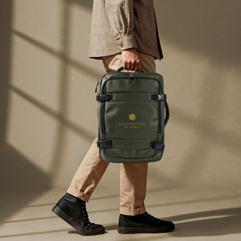 Sac à dos vert kaki porté à la main par un homme, illustrant la position du marquage sur la face avant. Avec marquage visible.