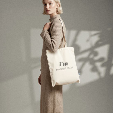 Tote bag Fairtrade porté à l’épaule, illustrant la souplesse du tissu et présentant un marquage visible sur la face avant.