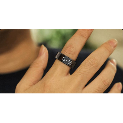 Gros plan de la bague portée au doigt, l’écran allumé affichant des informations numériques visibles en façade dans un style dis