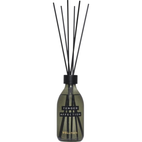 Diffuseur en verre vert fumé présenté avec des bâtonnets noirs insérés dans le col et un bandeau frontal visible sur la face ava