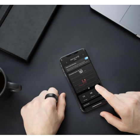 Bague connectée portée au doigt, utilisée avec une application active sur smartphone affichant des données ; aucune personnalisa