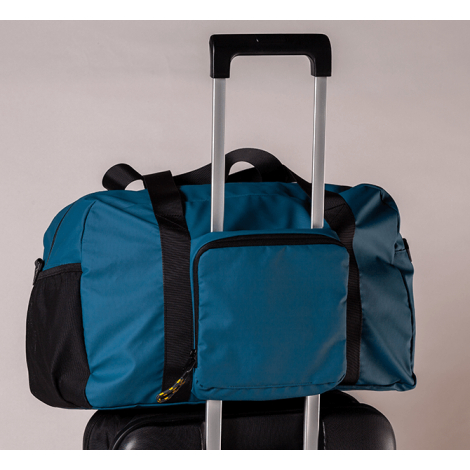 Vue arrière du sac fixé sur la poignée d’une valise, montrant une grande poche zippée utilisée comme passant de trolley, sans ma