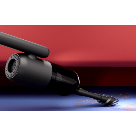 Vue rapprochée de l’aspirateur en fonctionnement, tenu incliné avec embout brosse en train d’aspirer des particules sur une surf