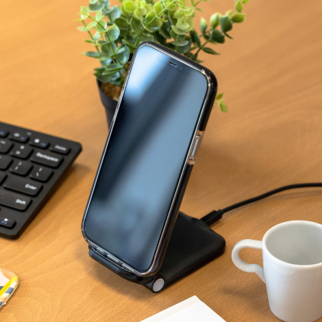 Chargeur induction branché sur bureau en bois avec smartphone posé dessus.