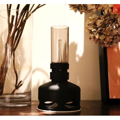 Lampe noire allumée dans un intérieur sombre, cheminée éclairée et corps foncé visibles, sans marquage apparent sur cette vue.