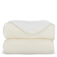 Couverture blanche pliée montrant la face pelucheuse contrastant avec la face lisse, sans marquage apparent.