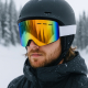 Masque de ski porté par un homme, montrant l’écran miroir coloré et la sangle blanche, sans marquage visible depuis cet angle. Masque de ski porté par un homme, montrant l’écran miroir coloré et la sangle blanche, sans marquage visible depuis cet angle.