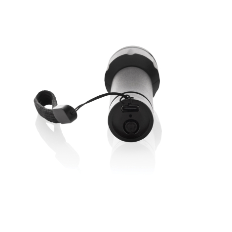 Lampe torche couchée sur fond blanc, vue arrière montrant le bouton de commande, le port de recharge et la fixation de la dragon