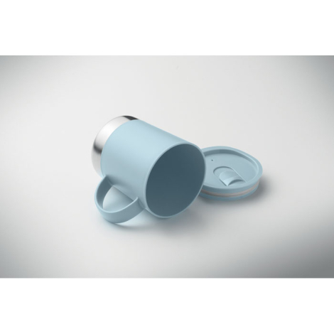 Mug à paroi simple présenté couché sur surface claire sans couvercle, avec le couvercle posé à côté et la base en acier inoxydab