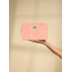 Trousse rectangulaire de couleur rose corail, vue de face, tenue dans une main sur fond uni, fermeture zippée située sur le côté Trousse rectangulaire de couleur rose corail, vue de face, tenue dans une main sur fond uni, fermeture zippée située sur le côté