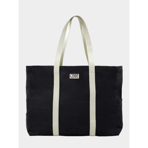 Sac de plage noir vu de face avec anses longues écrues et étiquette avec marquage visible.