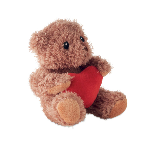 Vue de profil d’un ours en peluche sur fond blanc montrant le volume du corps, les pattes et le cœur rouge tenu contre la poitri