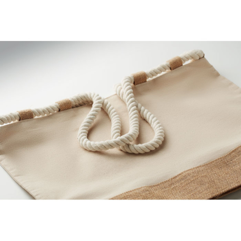 Détail du haut d’un sac de plage en toile écrue montrant les poignées en corde et les passants en jute cousus le long de l’ouver
