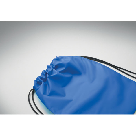 Détail du haut d’un sac à cordon enfant bleu montrant la matière textile et le passage des cordons noirs dans l’ourlet, sans per
