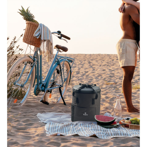 Sac à dos isotherme posé sur une plage à côté d’un vélo et d’une personne, face avant visible avec personnalisation apparente su