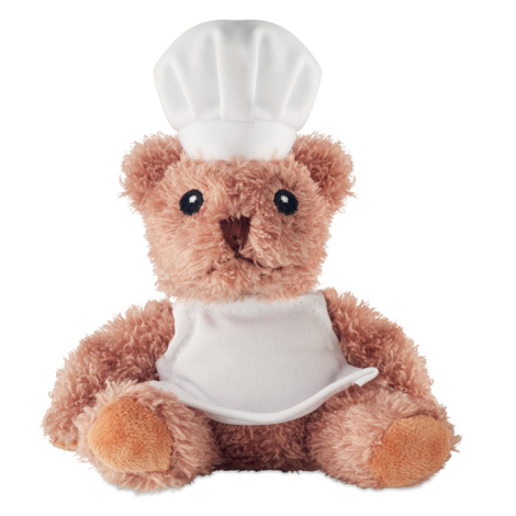 Assis de face sur fond blanc, l’ours en peluche porte une tenue de chef cuisinier avec toque et tablier unis, visage entièrement