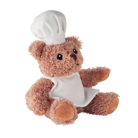 Présenté assis de profil sur fond blanc, un ours en peluche chef cuisinier avec toque, tablier et pattes visibles, sans marquage