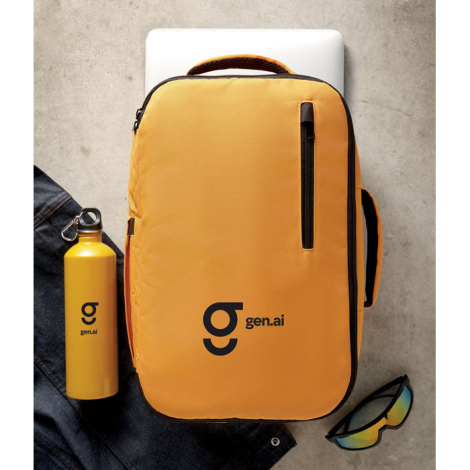 Mis en situation au sol sur fond clair, le sac à dos est vu de face avec accessoires disposés autour, avec personnalisation visi