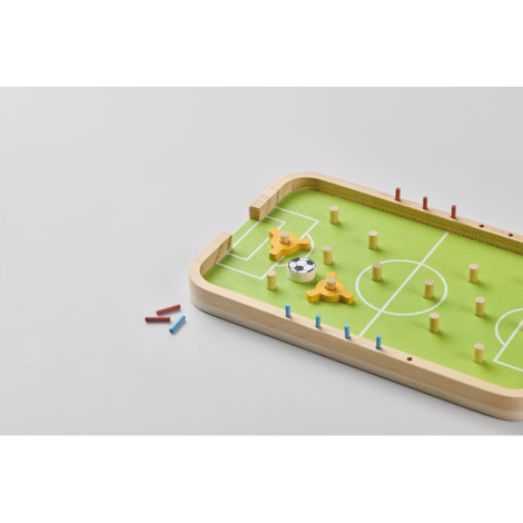 En vue partielle sur fond clair, le jeu de football de table montre la surface de jeu avec trous de positionnement, tandis que c