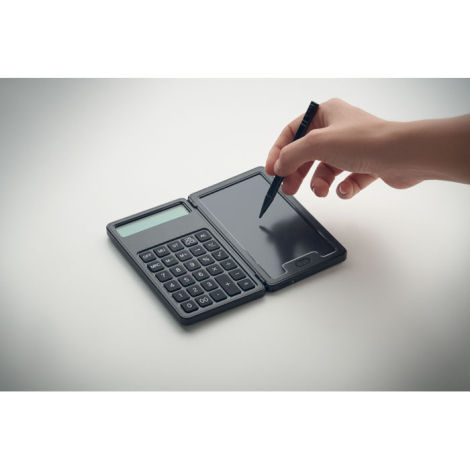 Posée ouverte sur une surface claire, la calculatrice est utilisée avec le stylet sur la tablette LCD, une main en train d’écrir