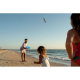 Frisbee utilisé en situation de jeu sur une plage, visible à distance entre des personnes en extérieur, sans personnalisation cl Frisbee utilisé en situation de jeu sur une plage, visible à distance entre des personnes en extérieur, sans personnalisation cl