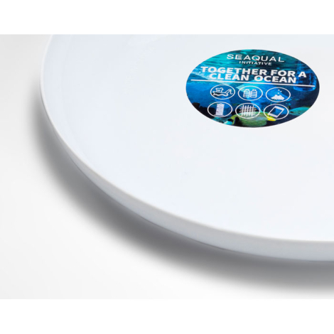 Détail rapproché d’un frisbee blanc montrant une étiquette circulaire apposée sur la face supérieure, personnalisation visible s