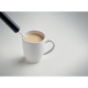 Mousseur à lait en situation d’utilisation au-dessus d’une tasse contenant une boisson mousseuse, tige et fouet plongés dans le 