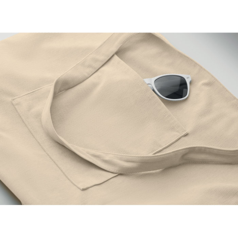 Détail du sac shopping en velours côtelé montrant la poche frontale ouverte et les longues poignées avec un accessoire glissé, s