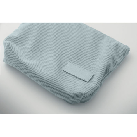 Trousse en velours côtelé présentée pliée de biais, texture du tissu et étiquette cousue visibles, sans personnalisation apparen