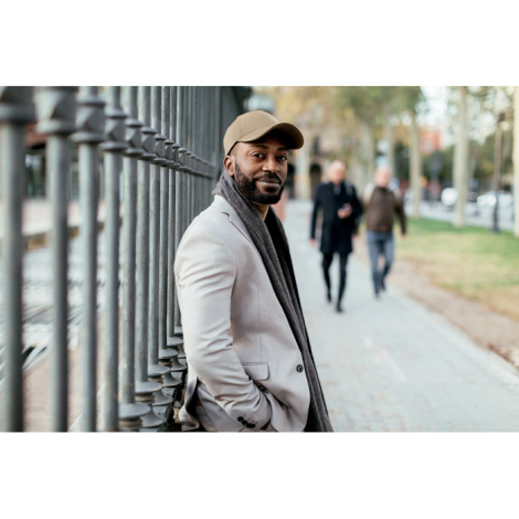 Casquette beige portée par un homme en extérieur, montrant la visière et la forme générale, sans marquage visible.