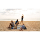 Tapis de plage posé sur le sable en extérieur avec plusieurs personnes assises ou allongées dessus, sans marquage visible. Tapis de plage posé sur le sable en extérieur avec plusieurs personnes assises ou allongées dessus, sans marquage visible.