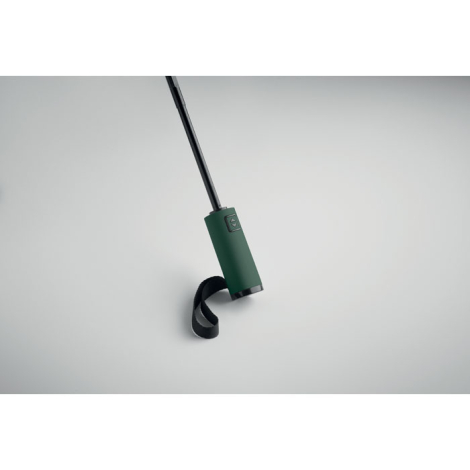 Gros plan sur la poignée d’un parapluie ouvert vert avec dragonne noire sur fond clair, sans personnalisation visible.