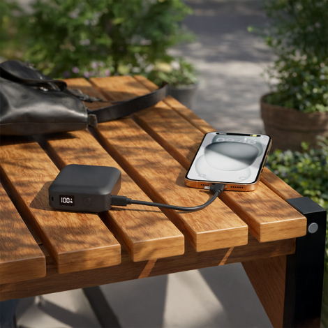 Batterie externe noire sur table en bois connectée à un smartphone ; aucune personnalisation visible.