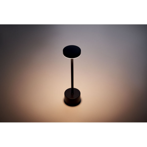Lampe de table en aluminium allumée dans un environnement sombre diffusant un éclairage circulaire vers le bas, sans personnalis