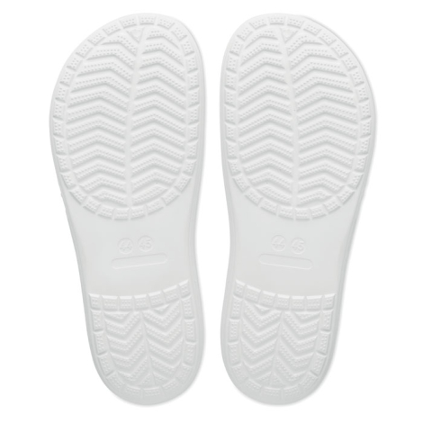 Vue de dessous d’une paire de tongs blanches sur fond clair montrant les semelles avec relief antidérapant, sans personnalisatio