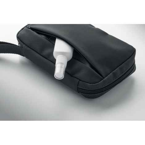 Vue rapprochée d’un flacon inséré dans la poche avant zippée de la trousse noire, sans marquage visible sur cette vue.