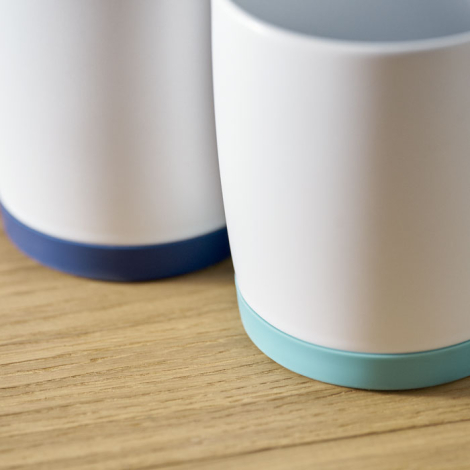 Vue rapprochée de la partie inférieure de deux mugs mettant en évidence la base en silicone colorée, sans marquage visible.
