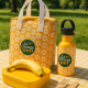Sac isotherme jaune à motif floral blanc posé sur une table en extérieur avec gourde assortie et boîte alimentaire, marquage cir