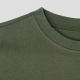Gros plan sur le col rond d’un T-shirt vert montrant la finition et les coutures, aucune personnalisation visible.