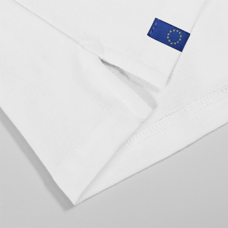 Gros plan sur la manche d’un polo blanc avec étiquette textile bleue et drapeau européen, marquage visible sur l’étiquette.