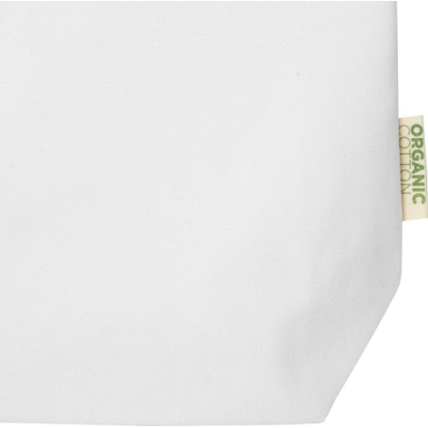 Gros plan sur la partie inférieure d’un sac écru avec étiquette textile latérale indiquant la composition, sans marquage visible