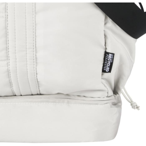 Vue rapprochée du côté d’un sac de voyage beige avec étiquette latérale, sans marquage visible.