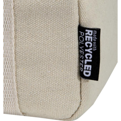 Gros plan sur l’angle inférieur d’un sac beige montrant la texture de la toile et une petite étiquette latérale cousue, illustré