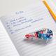 Correcteur Tipp-Ex Mini Pocket Mouse posé sur un cahier ouvert avec capot transparent et personnalisation visible sur la face la
