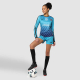 Femme en position avec un ballon, portant une tenue de sport avec un visuel imprimé en dégradé et un numéro sur le haut. Femme en position avec un ballon, portant une tenue de sport avec un visuel imprimé en dégradé et un numéro sur le haut.