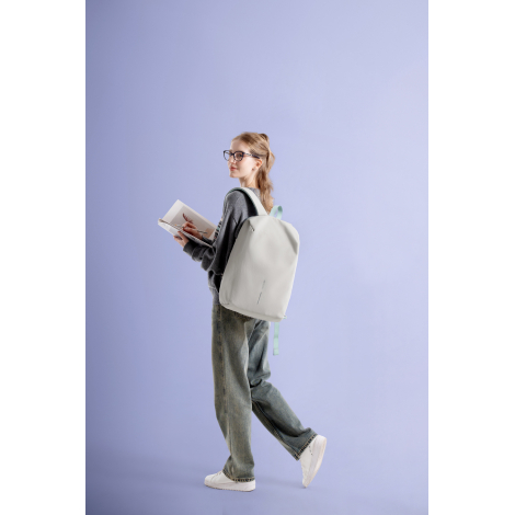 Sac à dos porté par une femme en mouvement avec un livre en main, sans personnalisation visible